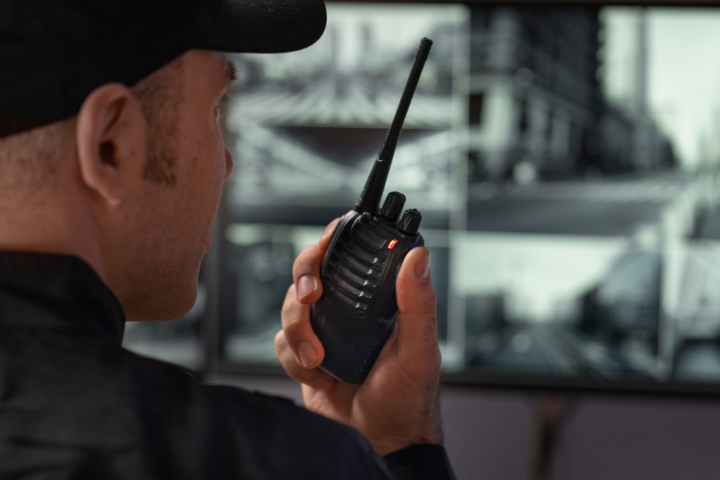 Profissional de segurança patrimonial utilizando rádio comunicador para coordenar a proteção de um ambiente.
